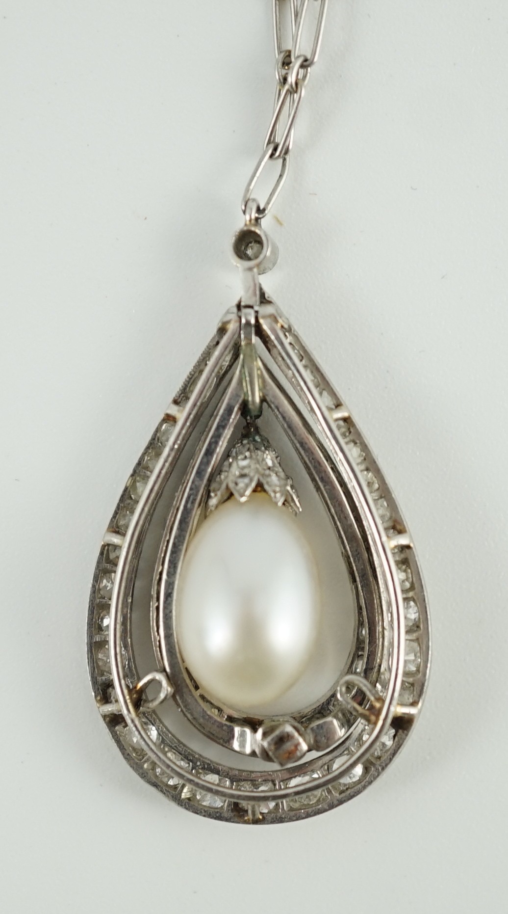 An early 20th century platinum, cultured? pearl and diamond cluster set pear shaped drop pendant necklace